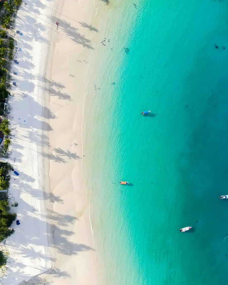 Aerial view of a white sand beach and turquoise water off Redang Island, with small boats on the sea