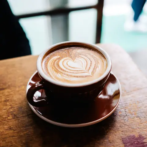 Flat white with heart latte art in a brown cup